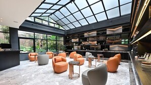 Un espace lounge moderne doté d’un plafond en verre, de sièges confortables et d’un bar offrant divers services.