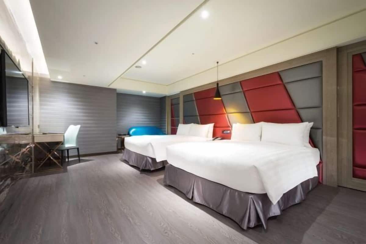A modern hotel room with two beds, a desk, and a chair.