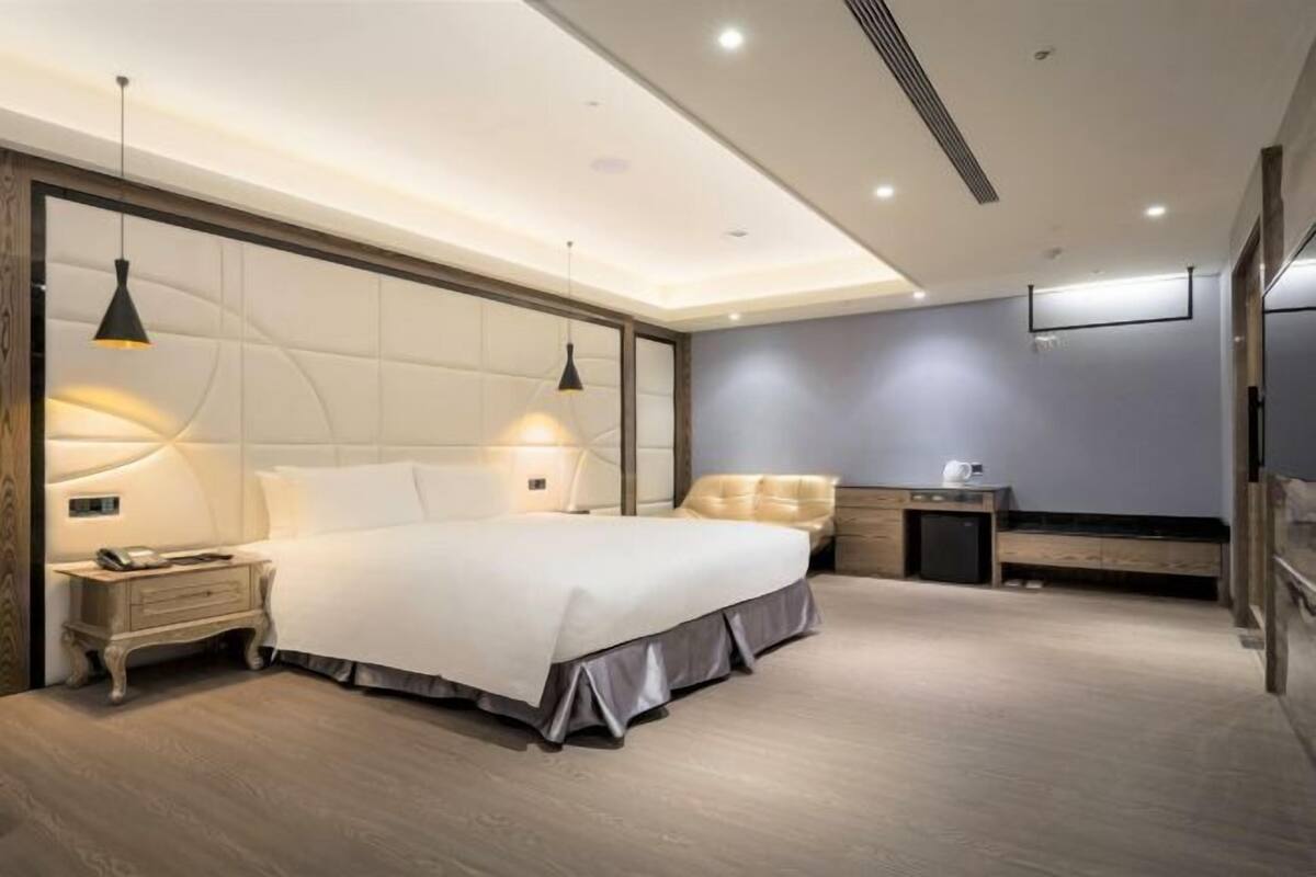 A modern bedroom with a large bed, bedside tables, a desk, and a wardrobe.