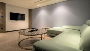 Un salon moderne avec un canapé vert clair, une table basse en marbre et un téléviseur à écran plat fixé au mur.
