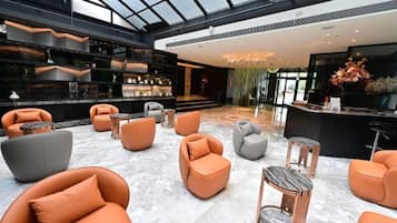 Un vestíbulo amplio con techo alto, zonas de estar, un mostrador de recepción y una zona de bar.