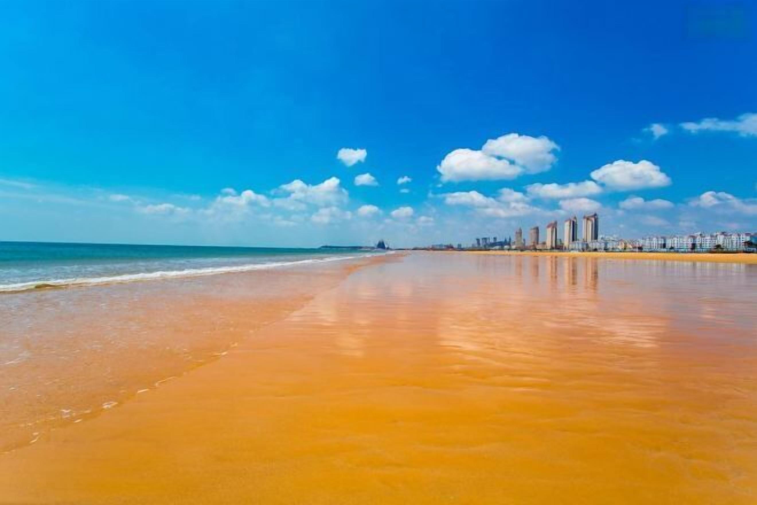 A beach with a clear sky and distant buildings.