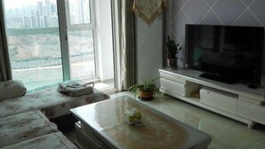 A living room with a large window, a flat-screen TV, a sofa, and a coffee table.