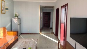 A living room with a sofa, a coffee table, a TV, and a hallway leading to another room.