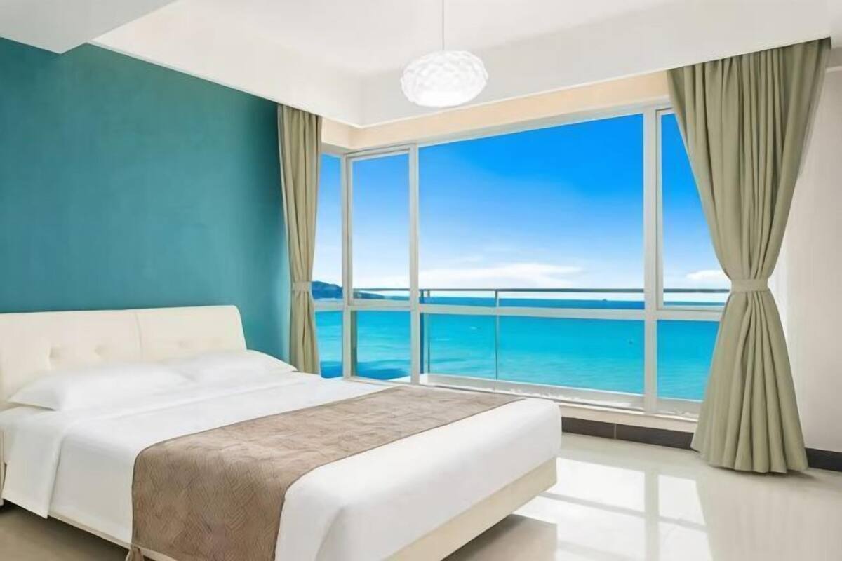 Ein Schlafzimmer mit einem großen Bett, Meerblick und einem Balkon.