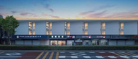 A multi-story building with a flat facade, multiple windows, and a parking lot with directional arrows.