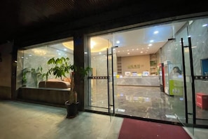 A hotel entrance with a reception desk, seating area, and a glass door. - Jindu Hotel Danghu Street (Pinghu)