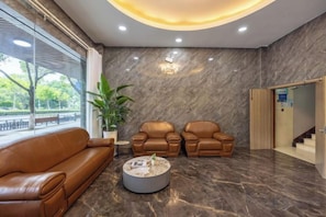 A lobby with a brown leather sofa, two armchairs, a coffee table, and a potted plant. - Jindu Hotel Danghu Street (Pinghu)