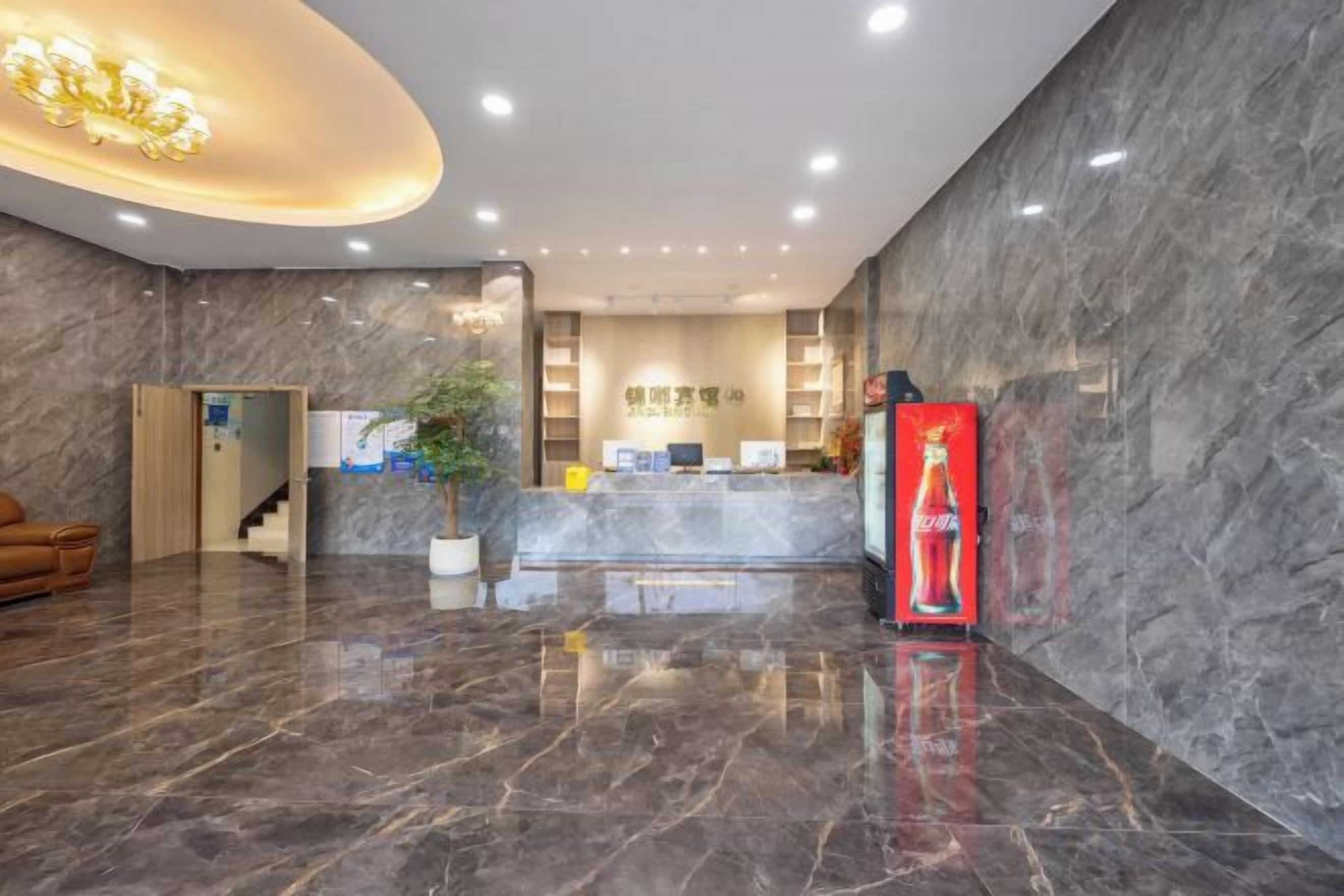 Un vestíbulo de hotel con una recepción, una escalera y un refrigerador de Coca-Cola.