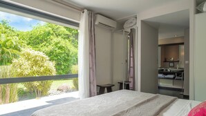 A bedroom with a large window, a bed, a bathroom, and a view of greenery outside. - Very nice villa Indigo overlooking golf court (Saint François)