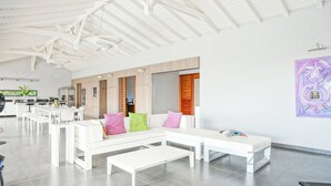 A modern, spacious living area with a white sectional sofa, a dining table, and a kitchen in the background. - Very nice villa Indigo overlooking golf court (Saint François)