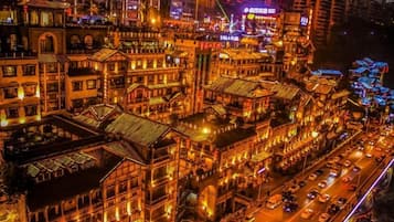 A densely packed urban street at night with traditional architecture and illuminated signage.