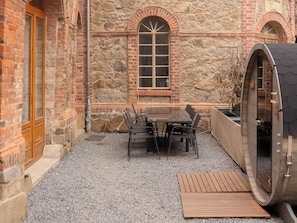 Un bâtiment en pierre avec une table et des chaises en bois, une fenêtre et un sauna.