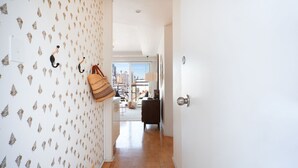 A hallway with patterned wallpaper, a wooden floor, and a view of a cityscape through a glass door. - Harbour the Sun, McMahons Point Isyd (McMahons Point)