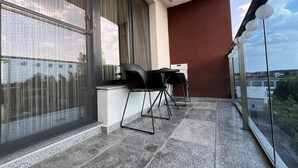 Ein Balkon mit Tisch und Stühlen, großen Fenstern und Blick auf die Stadt.