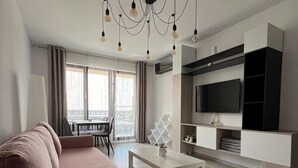Ein modernes Wohnzimmer mit einer Couch, einem Couchtisch und einem an der Wand befestigten Fernseher.