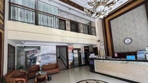Un hall d’hôtel comprenant un comptoir d’accueil, deux niveaux de balcons et un motif décoratif sur le sol.