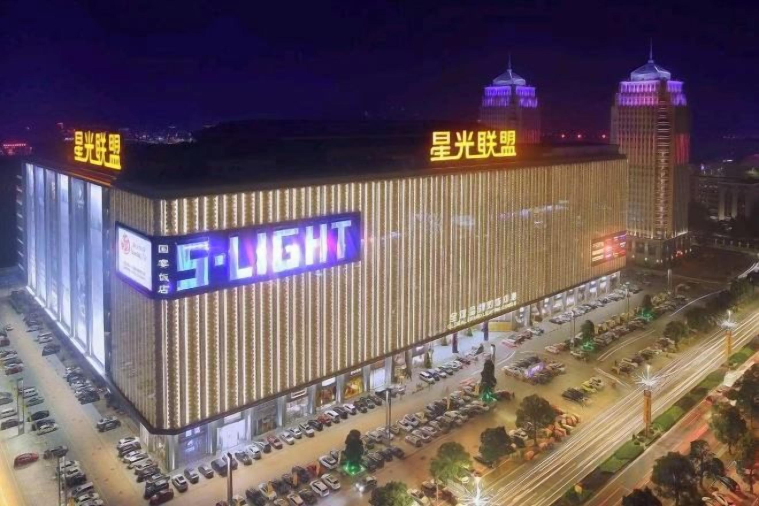 A large building with illuminated signage and a parking lot.
