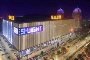 Um edifício grande com letreiros iluminados e um estacionamento.