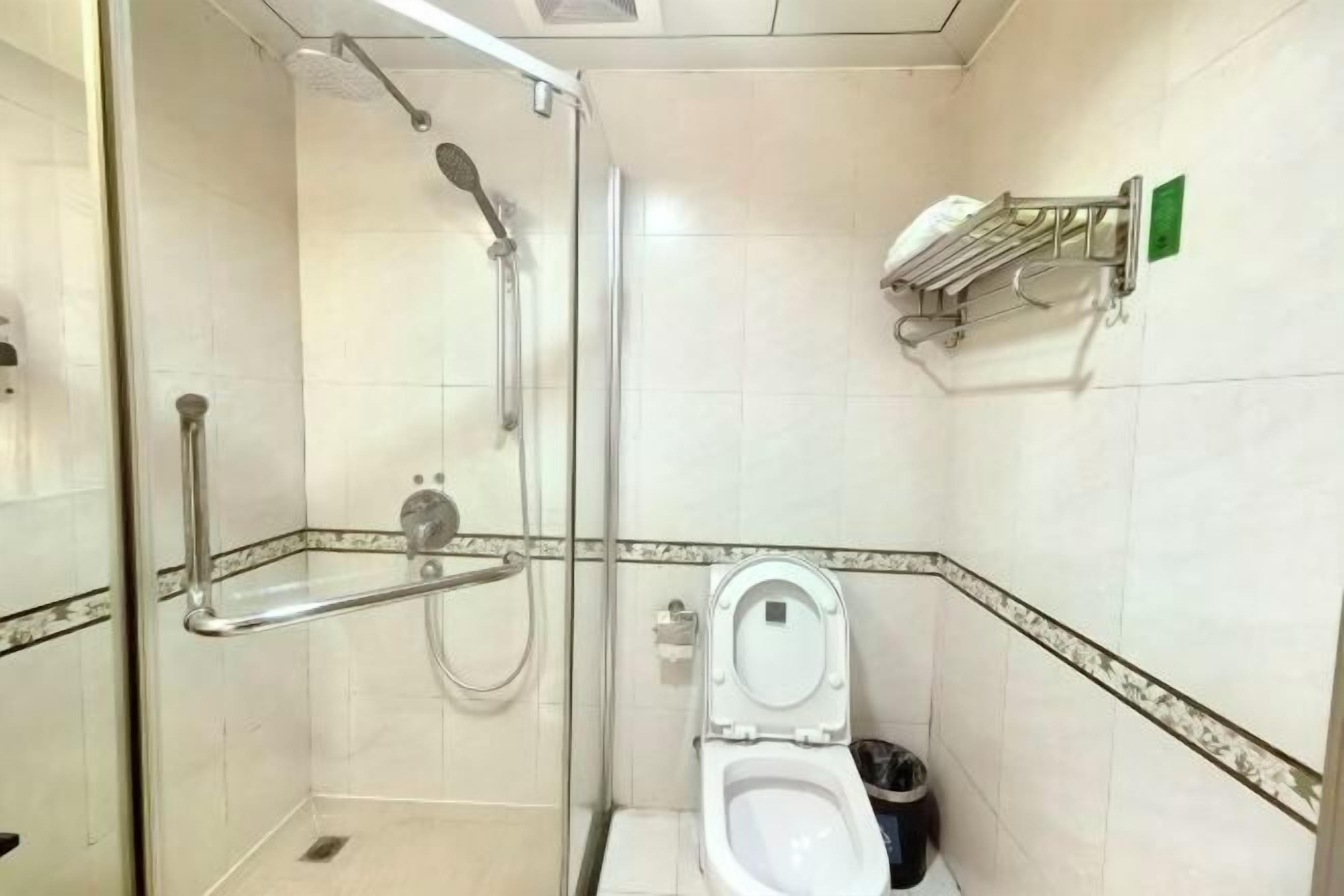 A small, enclosed bathroom with a shower, toilet, and hand sanitizer dispenser.