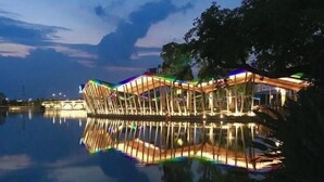 Une structure moderne et illuminée, située au bord d’un plan d’eau paisible, au crépuscule.