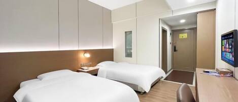 A hotel room with two beds, a desk, and a television.