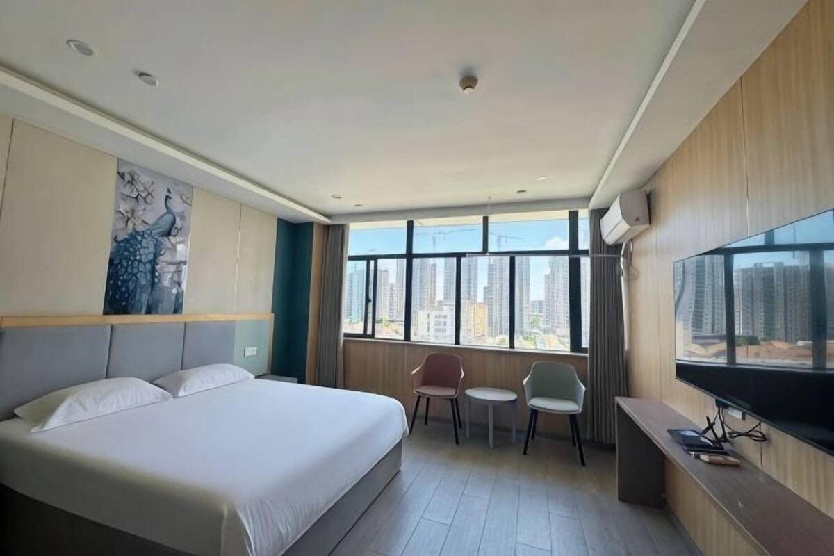 A hotel room with a bed, a TV, a desk, and a chair.