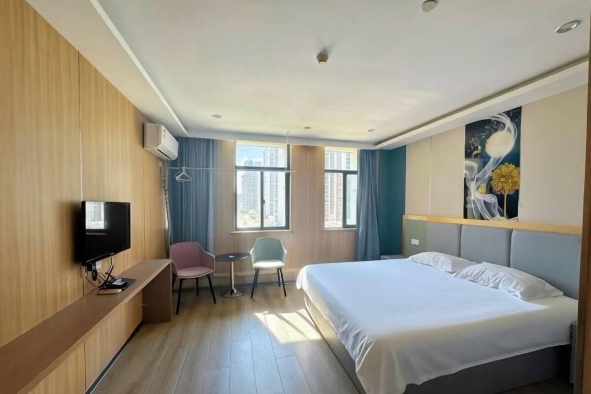 A hotel room with a bed, a TV, a desk, and two chairs.