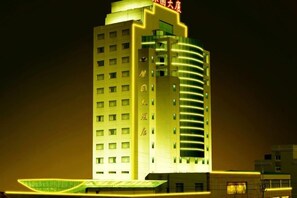 A multi-story hotel with a prominent curved facade and illuminated signage.