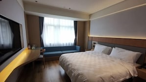 Een hotelkamer met een bed, een bureau, een raam met gordijnen en een televisie.
