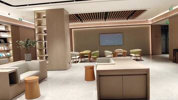 A modern lobby with a central seating area, a large screen, and a bookshelf.