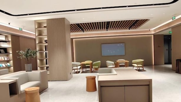 Een moderne lobby met een receptiebalie, zithoek en boekenkasten.