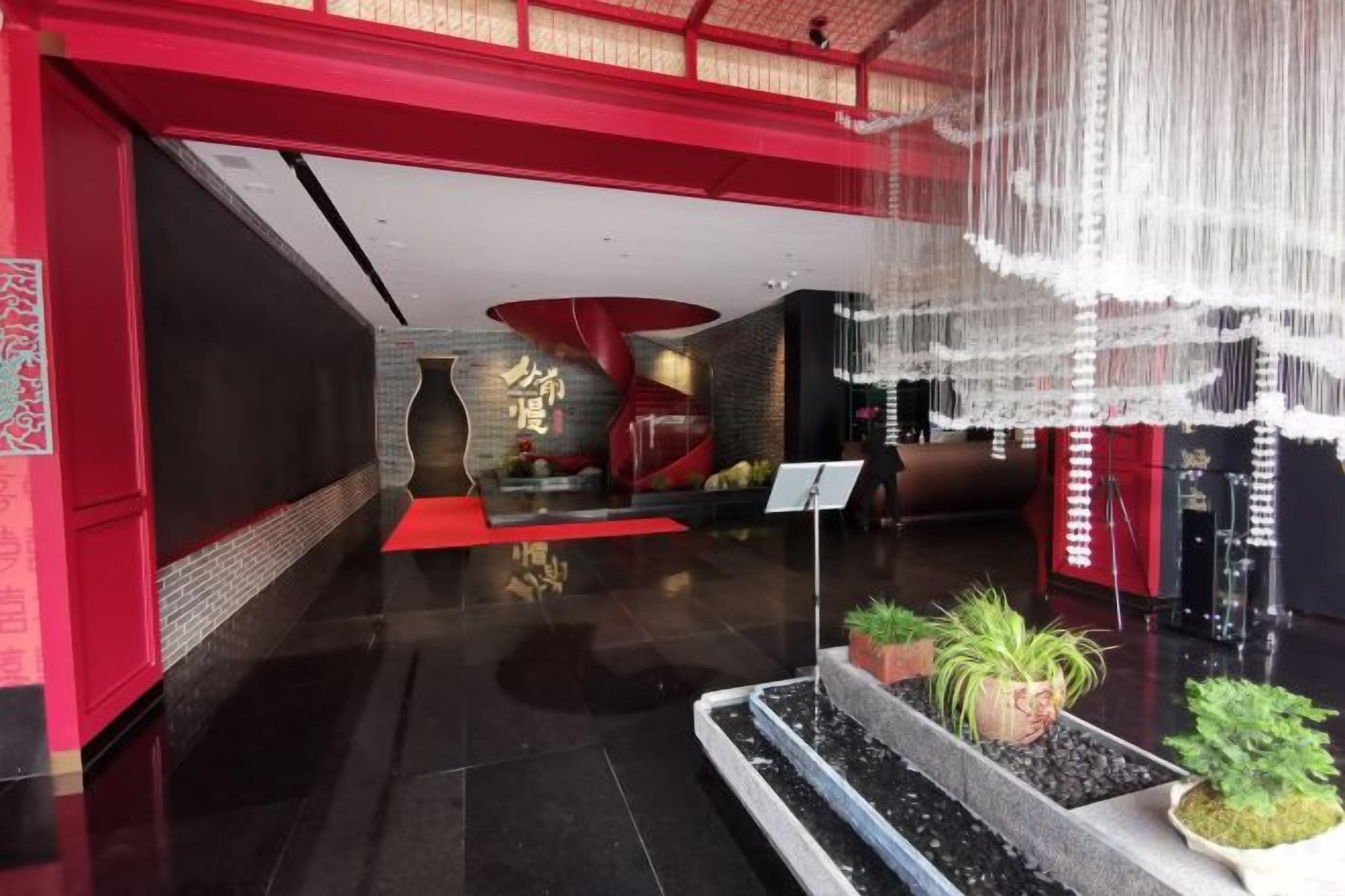 Un vestíbulo con una decoración en tonos rojo y negro, una recepción y una zona de estar con alfombra roja.