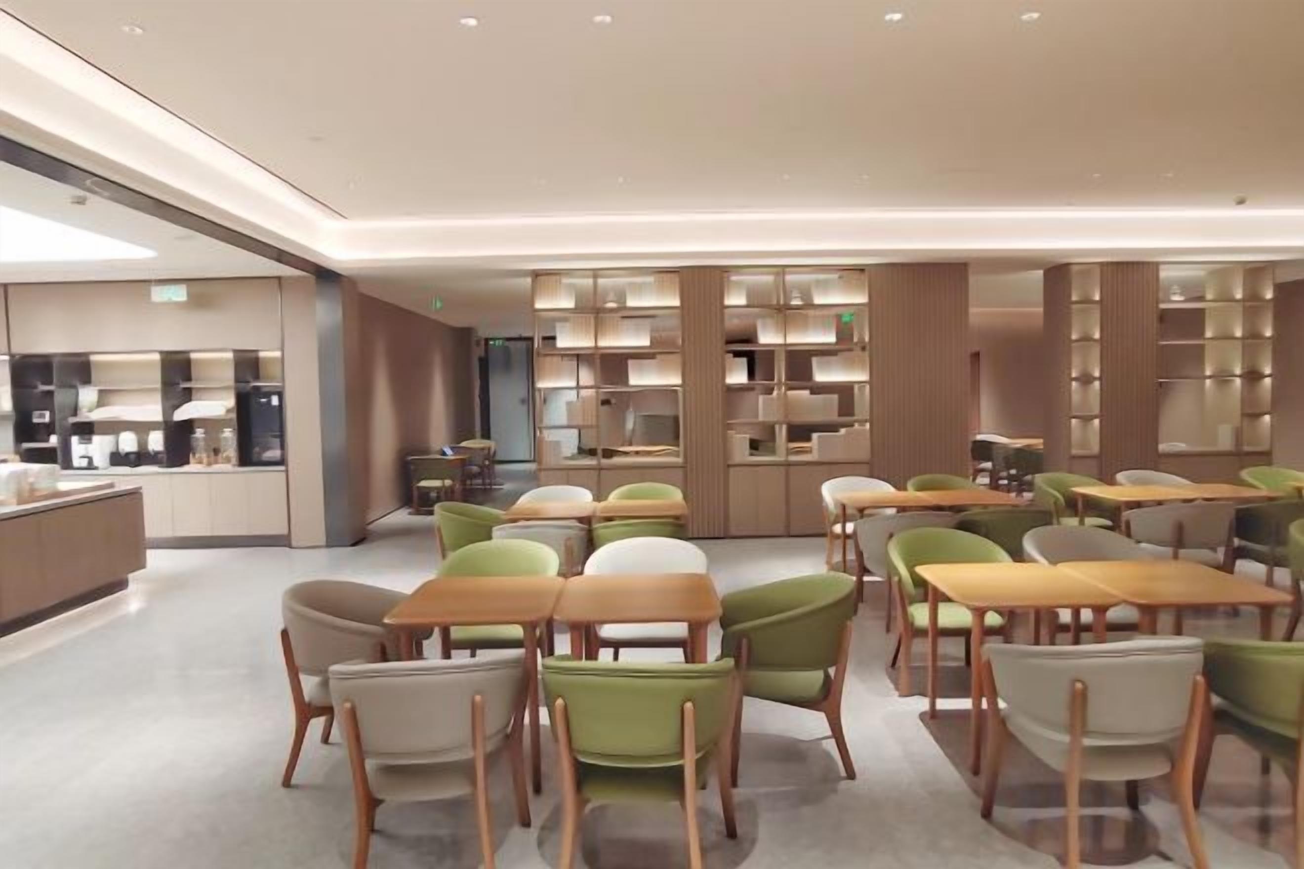 A modern dining area with tables and chairs, a counter, and shelves with items.