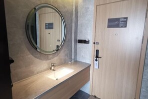 A modern bathroom with a round mirror, a sink, and a wooden door. - Yinyuan Grand Hotel (Tongxiang)