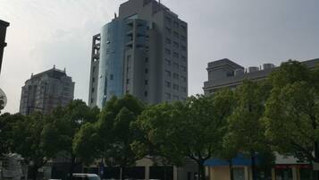 A multi-story building with a modern design, surrounded by trees and parked cars.