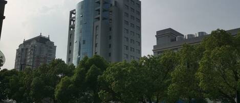Un edificio moderno de varios pisos, rodeado de árboles y coches aparcados.