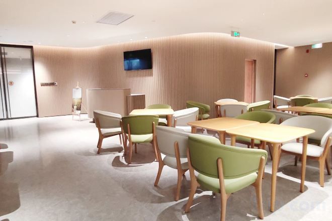 A modern conference room with tables and chairs, a flat-screen TV, and a curved wall design.