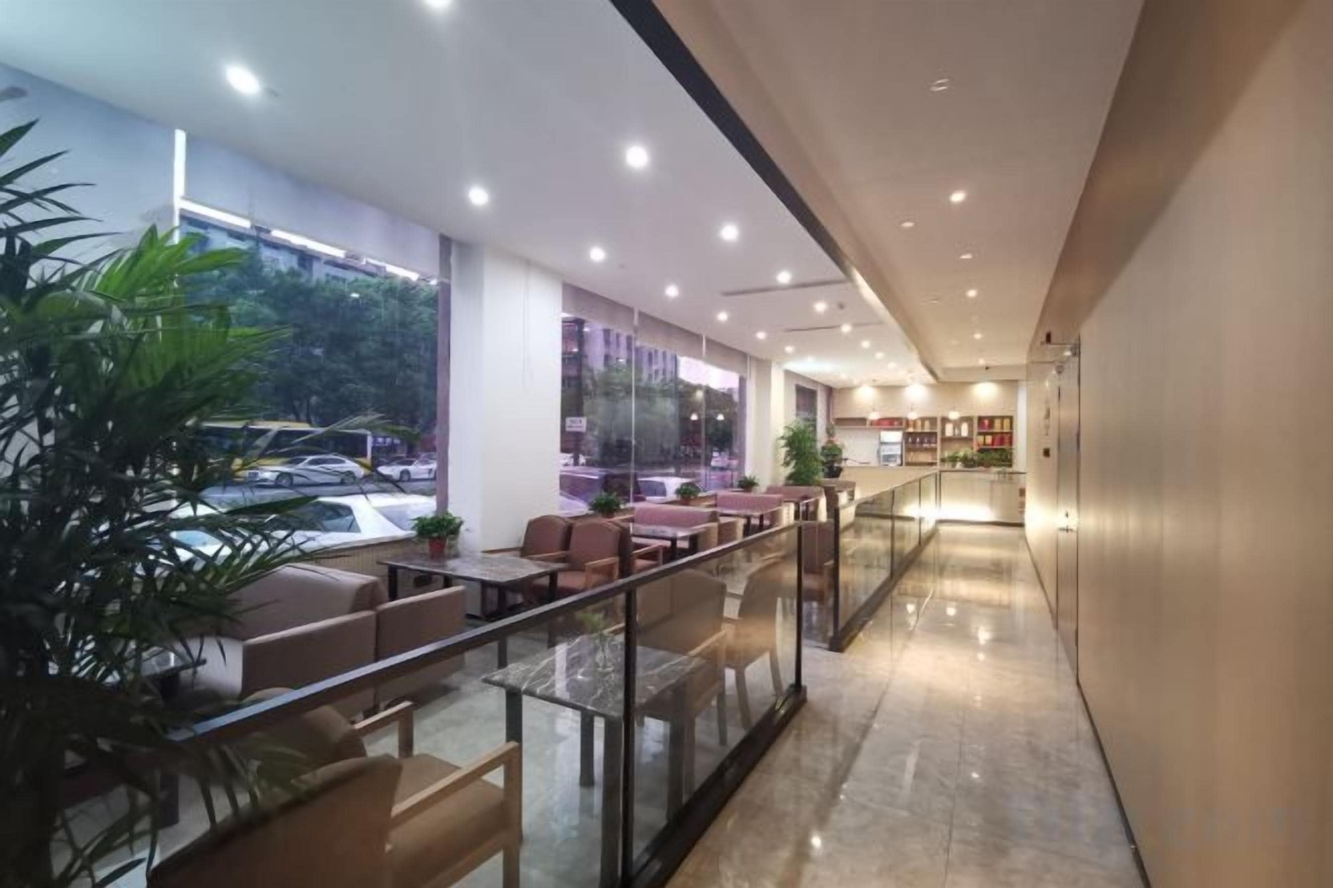 A modern hotel lobby with a glass railing, seating area, and a view of the street.