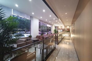 Een moderne hotelentree met glazen balustrade, een zithoek en uitzicht op de straat.