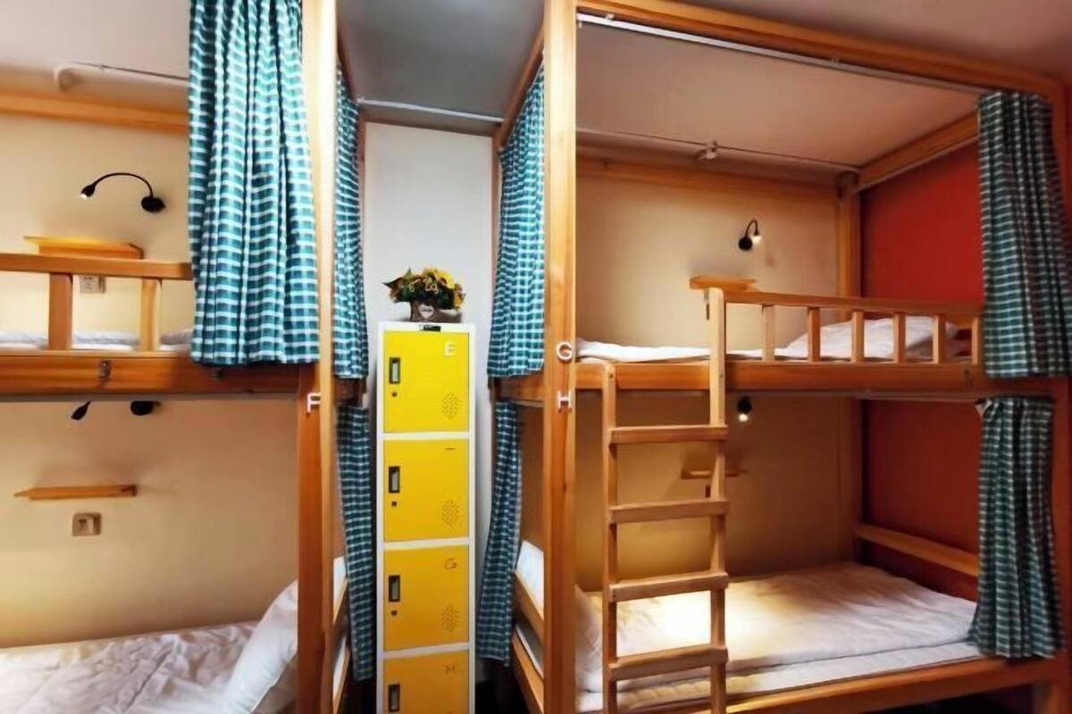 Une chambre avec un lit superposé, une échelle en bois, une petite table et un placard jaune.