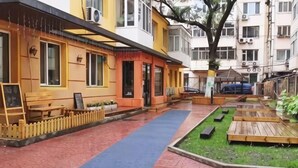 A courtyard with a paved walkway, wooden benches, and a small garden area. - Daoxiang International Youth Hostel(Harbin Central Avenue) (Harbin)