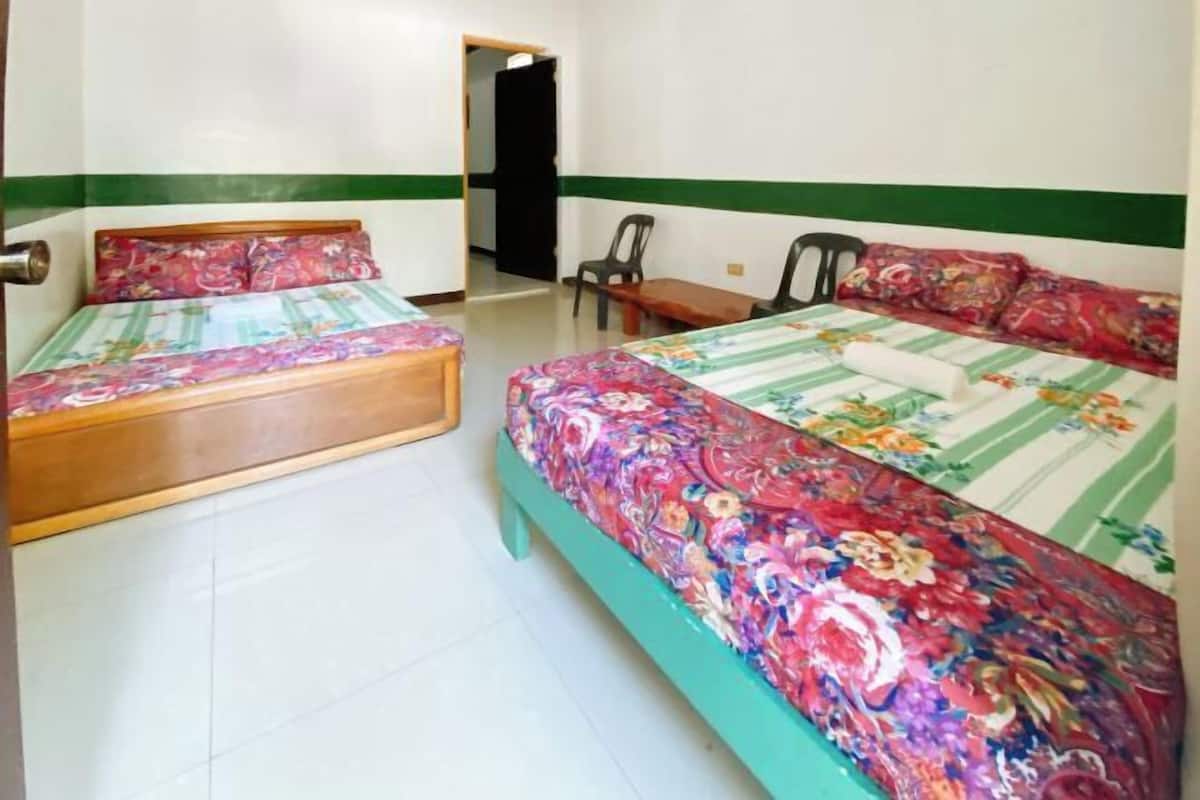 A room with two beds, a chair, and a small table.