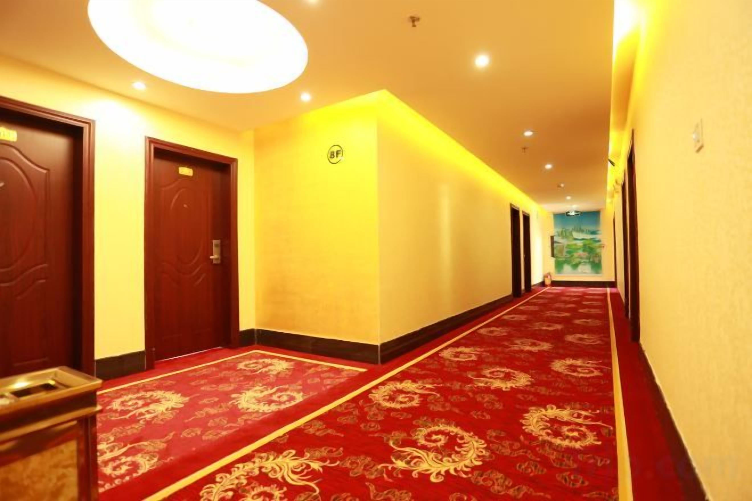A hotel corridor with a red carpet, doors, and a ceiling light fixture.