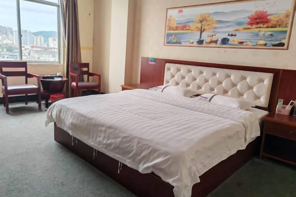 Une chambre d’hôtel avec un grand lit, une chaise, une petite table et un tableau au mur.