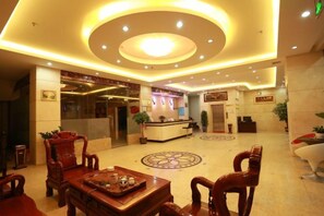 A hotel lobby with a reception desk, seating area, and a decorative floor pattern. - JH HOTEL (Dongxing)