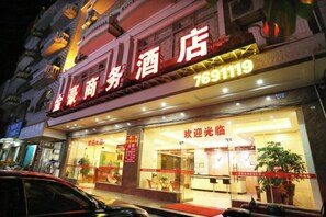 A hotel with a large illuminated sign, a reception area, and a visible entrance. - JH HOTEL (Dongxing)