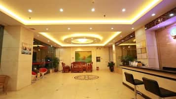 A hotel lobby with a reception desk, seating area, and a decorative floor pattern.