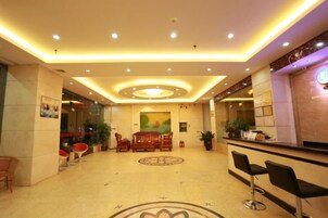 Un hall de hotel con mostrador de recepción, zona de estar y un diseño decorativo en el suelo.