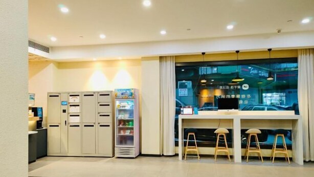 A hotel lobby with a reception desk, vending machines, and a seating area with stools. - HanTing Hotel (Jiande Xin'an River Xindian) (Jiande)